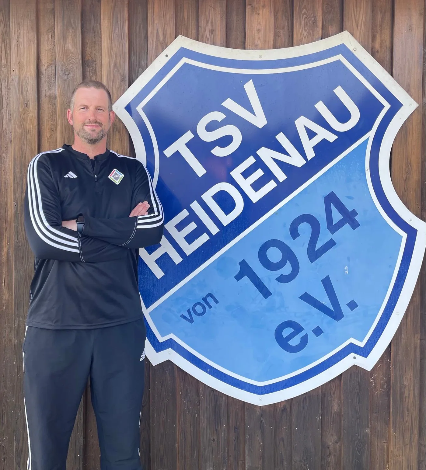 Kay Wichers als Jugendtrainer vor dem Vereinswappen des TSV Heidenau