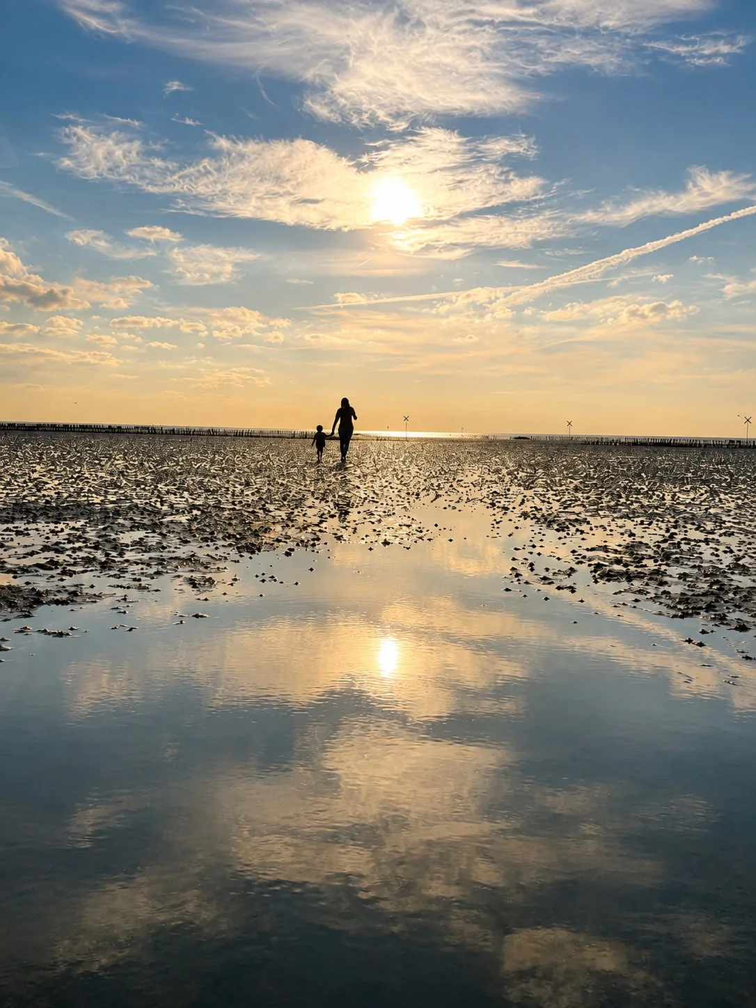 Stephanie Martens mit einem Kind im Watt bei Sonnenuntergang