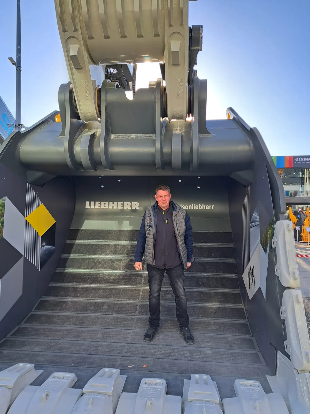 Torsten Martens vor der Schaufel einer großen Baumaschine